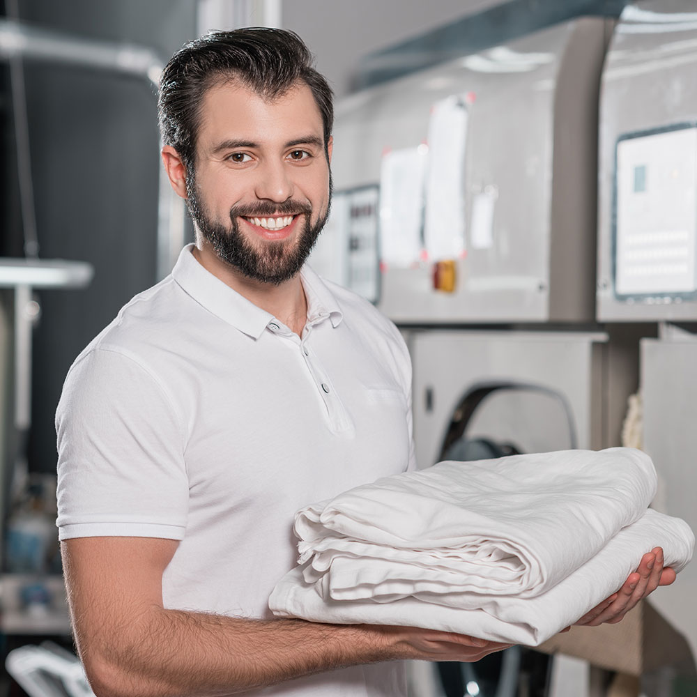 Smiling attendant holding a stack of freshly folded laundry