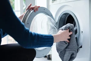 Person unloading clean laundry from a washing machine